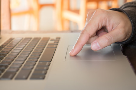 Woman's hand using touch pad of laptop, stock photo