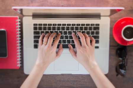 Woman's hand typing keyboard of laptop, stock photo