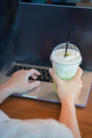 Woman Hand On Iced Milk Green Tea During Typing, stock photoの写真素材
