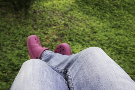 Jean woman hanging legs over green field, stock photo