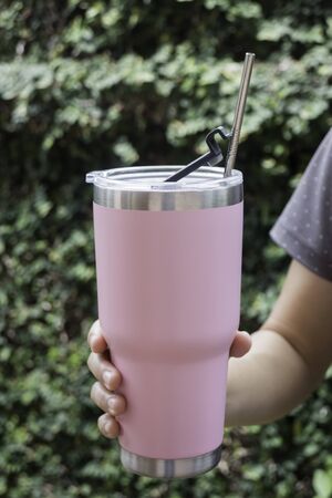Hand on tumbler mug with metal drinking straw