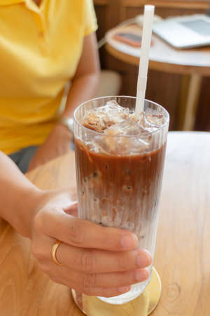 Hand on glass of iced coffee, stock photo
