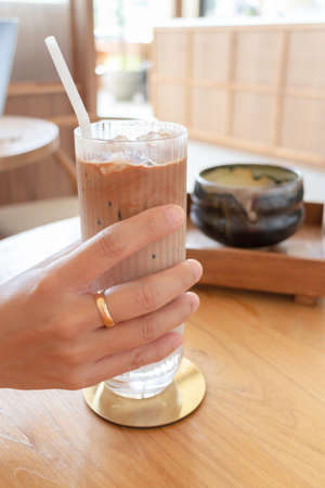 Hand on glass of iced coffee, stock photo