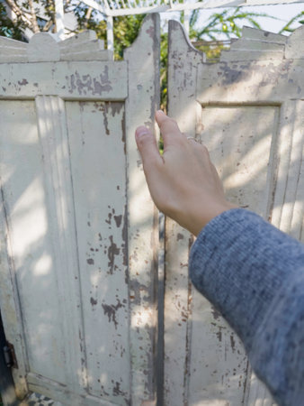Woman's hand pushing old wooden door in the garden. Selective focus.の写真素材