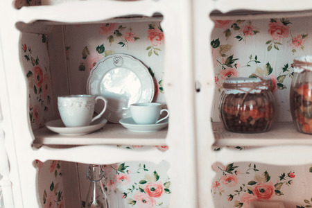 Beautiful white vintage wardrobe with ceramic dishes hanging on the wallの写真素材