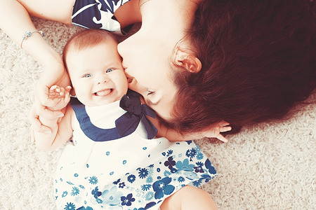 Beautiful little baby girl lies on a light carpet with mom. happy mother with baby