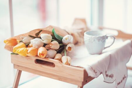 Beautifully decorated tray with a bouquet of tulips and a Cup of teaの写真素材