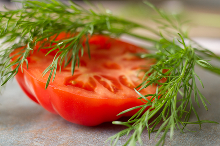 tomato cut with a knife on a gray background and dillの写真素材
