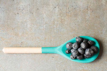blueberries and wooden spoon on a wooden tray