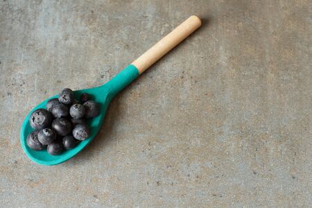 blueberries and wooden spoon on a wooden trayの写真素材