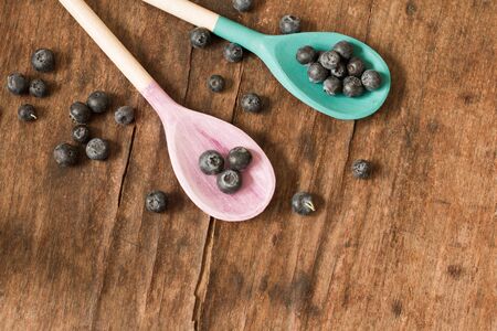 blueberries and wooden spoon on a wooden trayの写真素材