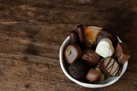Belgian chocolate in a white bowl on a wooden tableの写真素材