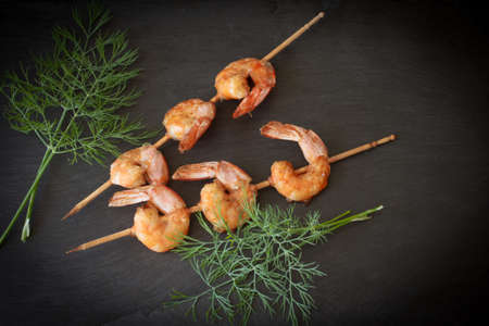 Grilled shrimp with dill on a black stoneの写真素材