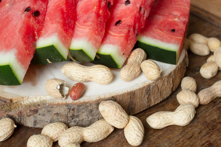 ripe red watermelon with peanuts on wooden background