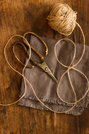 scissors lying on linen fabric with a rope on a wooden backgroundの写真素材