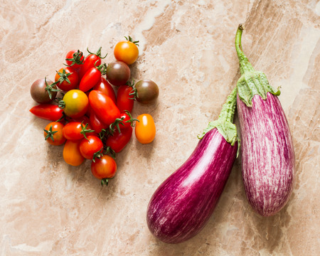 ripe eggplant and cherry tomatoes on a yellow background stoneの写真素材
