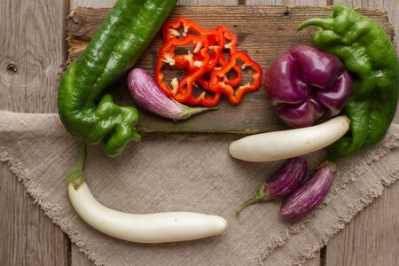 green pepper and basil and eggplant on a wooden cutting board and cloth made of cottonの写真素材