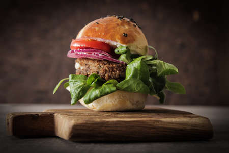 homemade veggie burger in a bun with sesame seeds of beer. delicious fast food for vegans. on a wooden backgroundの写真素材