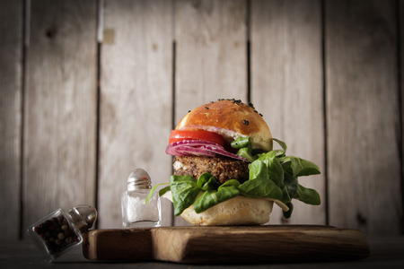 homemade veggie burger in a bun with sesame seeds of beer. delicious fast food for vegans. on a wooden backgroundの写真素材