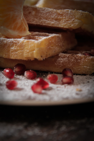 Square Belgian waffles with a tangerine and pomegranate and sprinkle with powdered sugarの写真素材