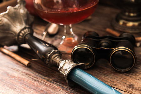 glass of cognac with stained binoculars and blue candle on a wooden background