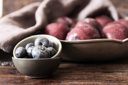 plum with blueberries ripe berries to the diet on a wooden backgroundの写真素材