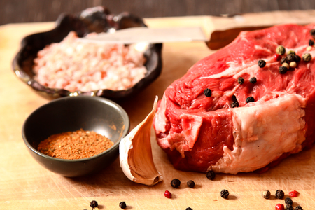 piece of raw meat with garlic and spices on a wooden backgroundの写真素材