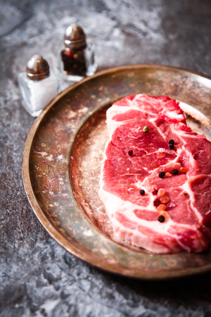 piece of raw meat beef on plate with peppers matelicheskoy on the background of stoneの写真素材