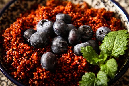Quinoa blueberries and raspberries on a plate with black background pattern woodの写真素材