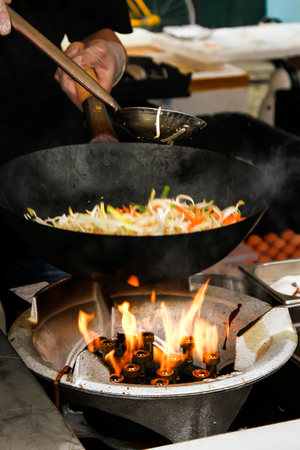 street food. fried noodles in a wok with chicken and shrimp on the open fireの写真素材