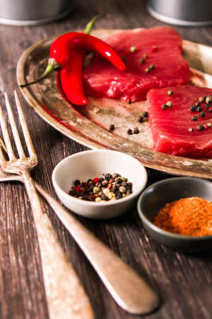 Tuna steak on a plate with chili peppers on  wooden backgroundの写真素材