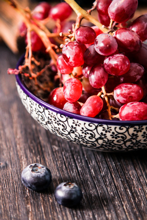blueberries and red grapes on a wooden background berry mixの写真素材
