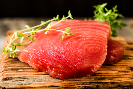 Tuna steak on a wooden board with pepper and cucumber, tasty fish dinnerの写真素材