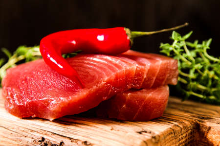 Tuna steak on a wooden board with pepper and cucumber, tasty fish dinnerの写真素材