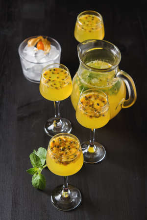 Alcoholic cocktail with fresh passion fruit with mint ice. Dark wood background.