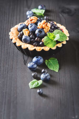 Homemade blueberry tart, walnut and mint on wooden tableの写真素材