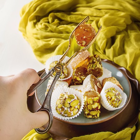 Eastern sweets. Turkish delight with pistachios in a vase. The fabric,  white background