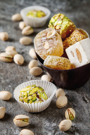 Eastern sweets. Turkish delight with pistachios in a vase. Dark stone background.の写真素材