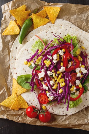 Ingredients for tacos or burrito making. Fresh organic vegetables and tortillas on rustic background, top view, place for textの写真素材