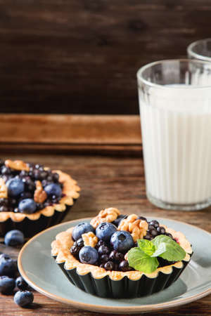 Homemade blueberry tart, walnut and mint with milk on a wooden tableの写真素材