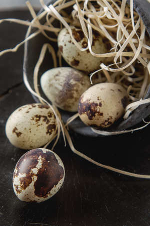 Little quail eggs in an old cup with a straw.  wooden tableの写真素材