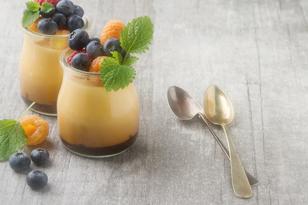 Milk Caramel dessert in a glass jar with berries. Gray wooden backgroundの写真素材