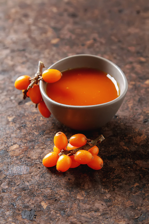Fresh sea buckthorn on a branch lying on  plate, juice. Dark wood backgroundの写真素材