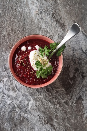 Traditional beetroot soup in a pink plate with Temyan, sour cream. Grey stone background. free space text.の写真素材