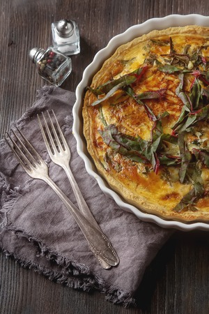 Traditional French cake. quiche with chard in white. Dark wood background. free space text. Top viewの写真素材