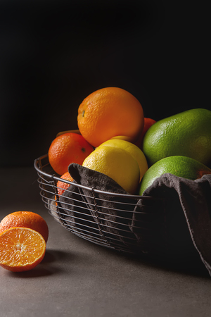 Different fresh citrus fruit in a basket on a gray background. Mix Lemon, orange, greyfruta Mandarinの写真素材