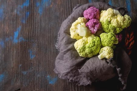 Rainbow of organic cauliflower and Romanesco broccoli on wooden tableの写真素材