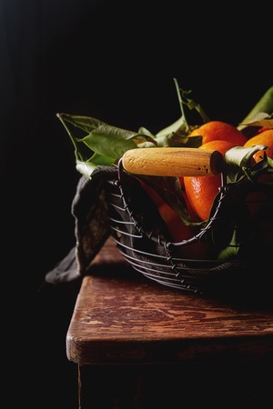 Orange ripe tangerine on the green branch with leaves. Dark wood backgroundの写真素材