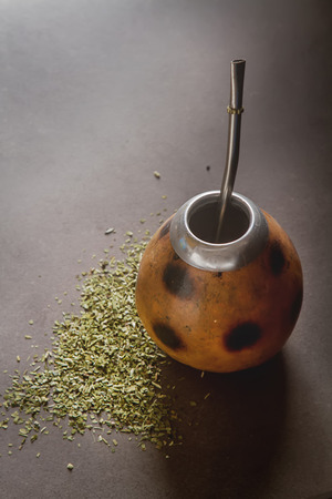 Traditional South American yerba mate tea in the calabash circle and Bombilla. Dark background