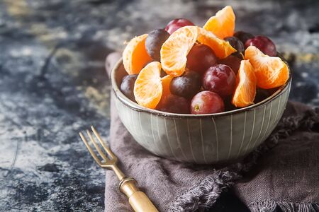 Plate with fruit salad of mandarin, grape, blueberry. Delicious and hearty breakfast options. Dark backgroundの写真素材